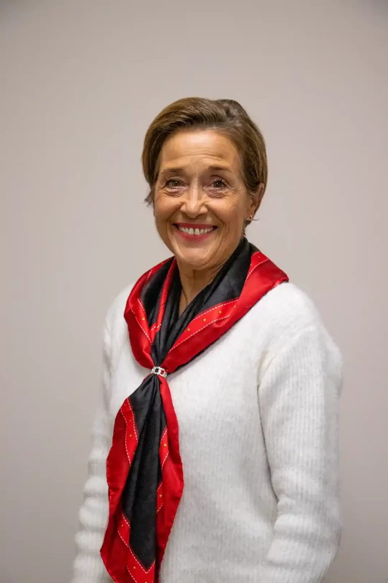Photo de Sylvie Marchand, présidente de l'ESVL, habillé en blanc avec une écharpe rouge et noir. Elle est dos à un mur neutre